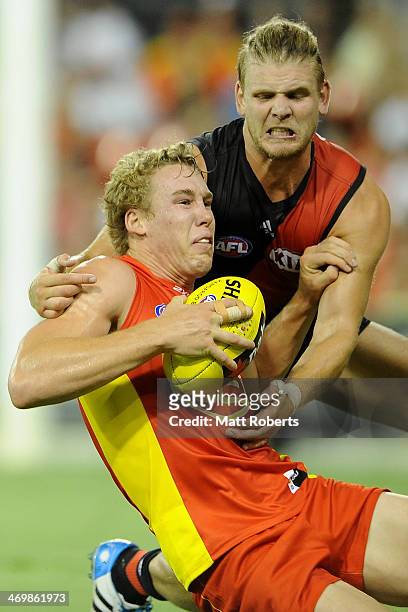 Tom Lynch of the Suns is tackled by Michael Hurley of the Bombers during the round two AFL NAB Challenge Cup match between the Gold Coast Suns and...
