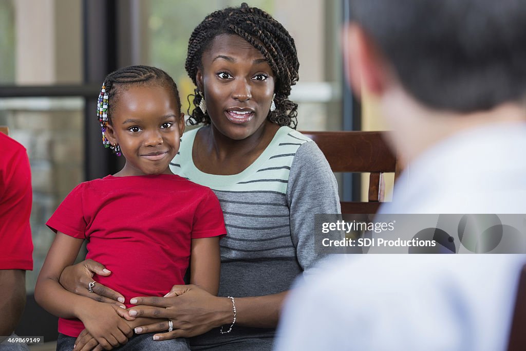 Mutter und Tochter mit einem Berater sprechen, während Familie Beratung