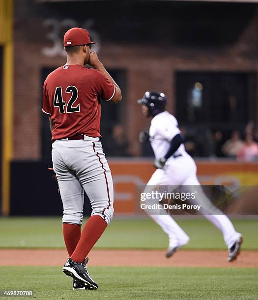 Randall Delgado of the Arizona Diamondbacks looks to the outfield as Justin Upton of the San Diego Padres rounds the bases after hitting a solo home...