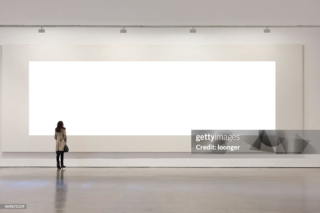 One woman looking at white frame in an art gallery