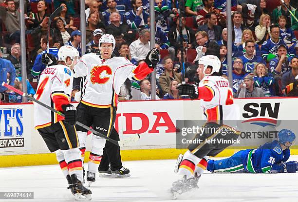 David Jones and Dennis Wideman congratulate goal scorer Kris Russell of the Calgary Flames while Yannick Weber of the Vancouver Canucks looks from...