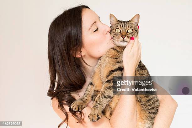 beautiful young woman kissing a cute striped cat - animals kissing stockfoto's en -beelden