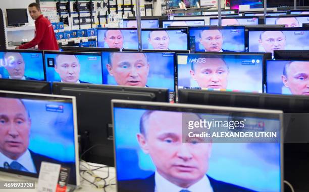 An employee stands by TV sets in a shop in Moscow on April 16, 2015 during the broadcast of Russian President Vladimir Putin's annual televised...