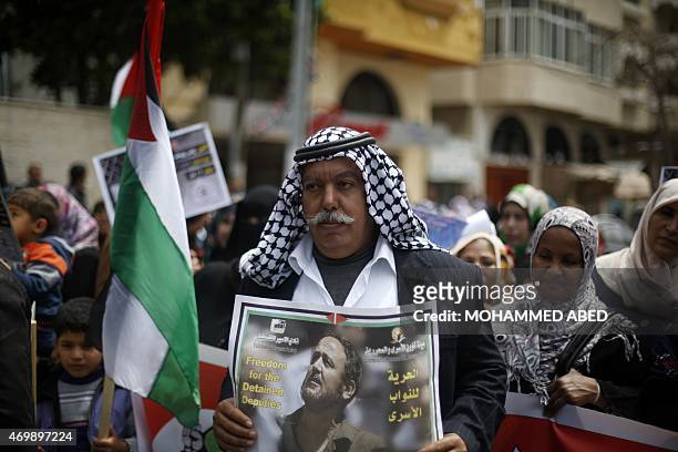 Palestinian man holds a portrait of Fatah leader Marwan Barghuti, who is imprisoned in an Israeli jail, during a protest marking Palestinian...
