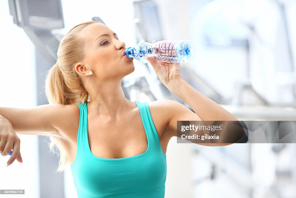 Woman drinking water in gym.