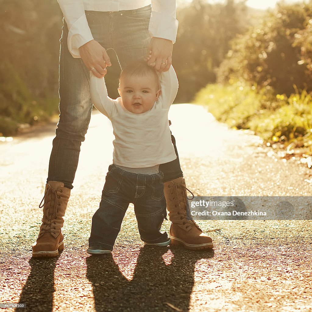 Baby boy walking with mother