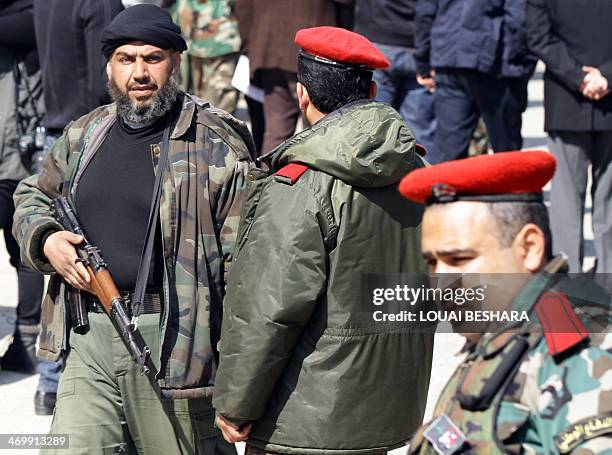 Rebel fighter walks past Syrian National Defence Forces , an armed unit of volunteers loyal to President Bashar al-Assad operating under Syrian army...