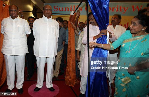 Chief Sharad Pawar poses with his wax statute as legendary singer Asha Bhosle looks on during the unveiling of their wax models at the MCA lounge of...