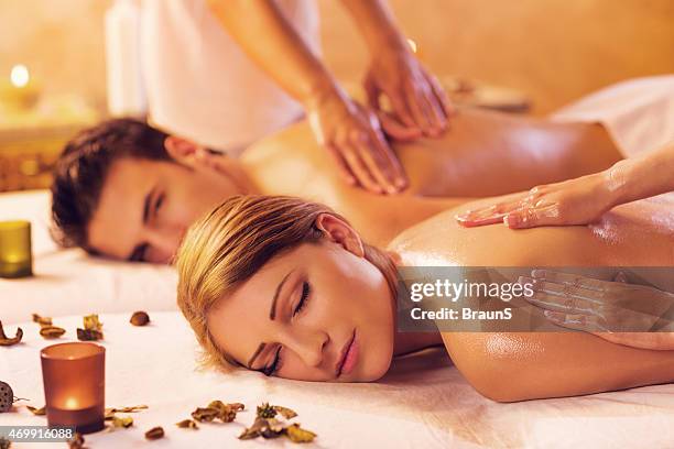 young couple relaxing during a back massage at the spa. - massage couple stock pictures, royalty-free photos & images