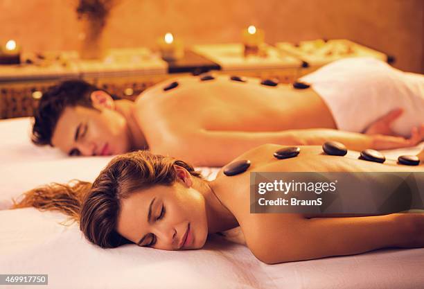 couple receiving hot stone therapy at the spa. - lastone therapy stock pictures, royalty-free photos & images