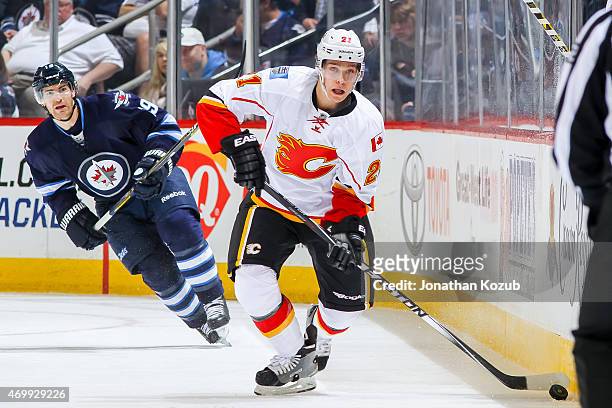 Mason Raymond of the Calgary Flames plays the puck up the ice as Jim Slater of the Winnipeg Jets gives chase during first period action on April 11,...