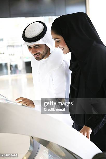 arab couple using touchscreen on mall kiosk - dubai shopping stock pictures, royalty-free photos & images