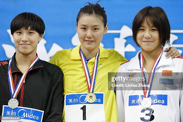 Silver medalist Zhu Menghui, Gold medal winner Liu Xiang and Bronze medalist Chen Xinyi celebrate on the podium after the Women's 50m freestyle final...