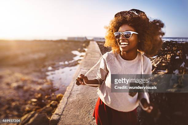 spielerisch afrikanische amerikanische teen hipster am strand - afro jokes stock-fotos und bilder