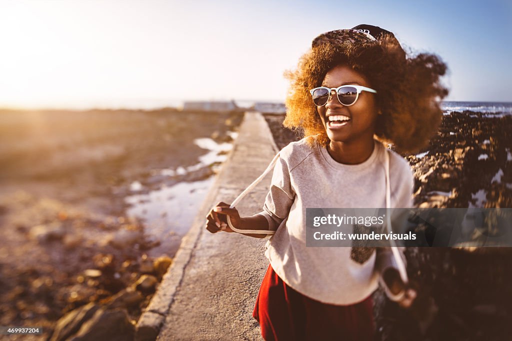 Divertida hipster adolescente afroamericana en la playa