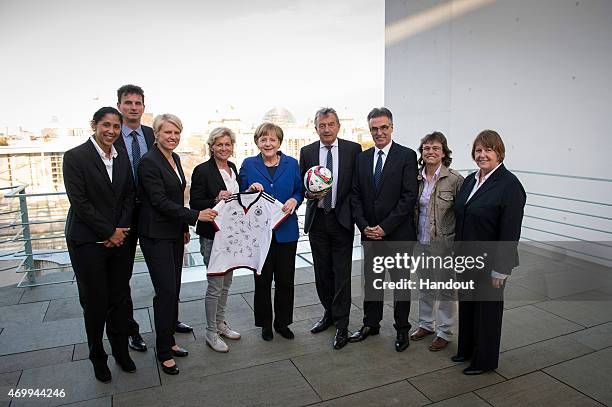 In this photo provided by the German Government Press Office , German Chancellor Angela Merkel holds a shirt with DFB President Wolfgang Niersbach...