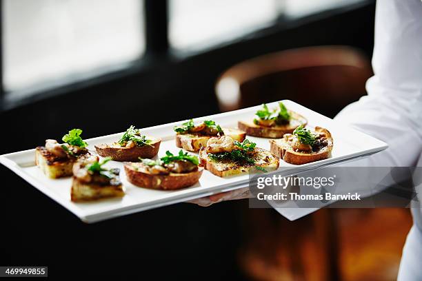 waitress holding platter of organic appetizers - mestiere nella ristorazione foto e immagini stock