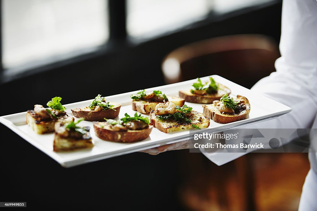 Waitress holding platter of organic appetizers