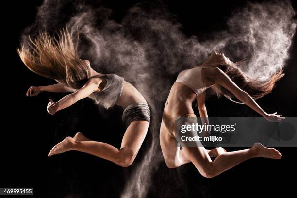 zwei frauen springen in einer wolke pulverschnee - modern dance stock-fotos und bilder