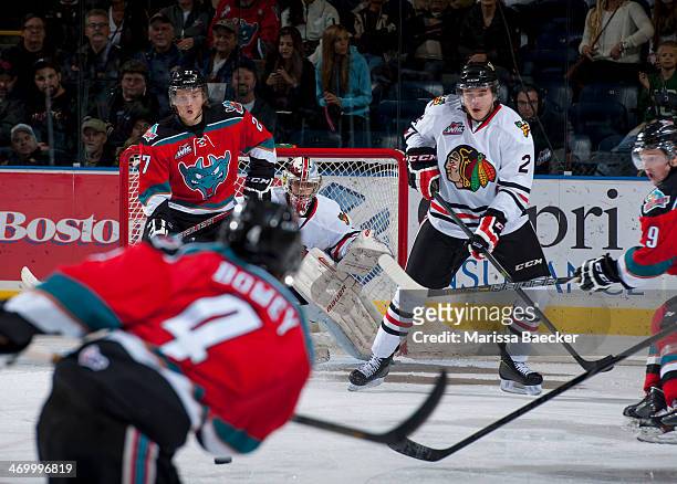 Brendan Burke of the Portland Winterhawks defends the net and watches the puck on a shot from Madison Bowey of the Kelowna Rockets between Ryan Olsen...