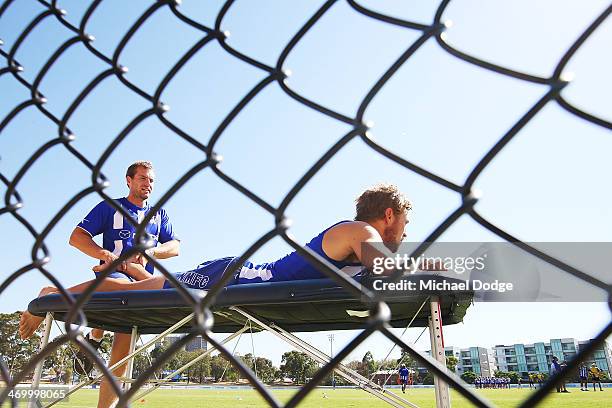 Kieran Harper looks on while receiving leg treatment during a North Melbourne Kangaroos AFL training session at Aegis Park on February 18, 2014 in...