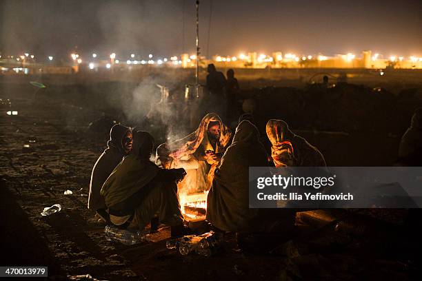 African asylum seekers gather around the fire in the early morning of a second day of protest outside the Holot detention centre where hundreds of...