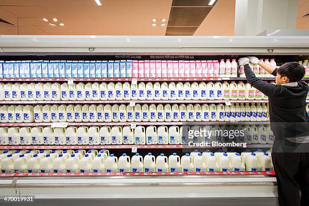 An employee arranges bottles of milk in the dairy section of a Coles supermarket, operated by Wesfarmers Ltd., in Sydney, Australia, on Tuesday, Feb....