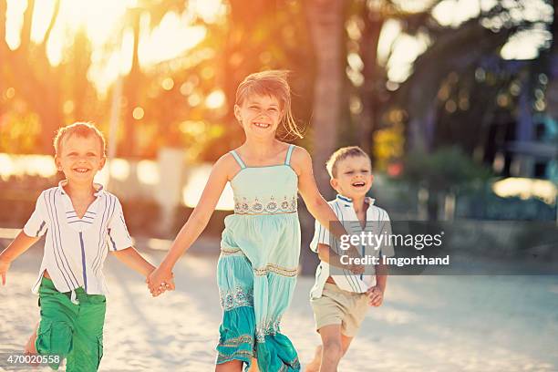 kinder laufen am strand - boy and girl running along beach holding hands stock-fotos und bilder