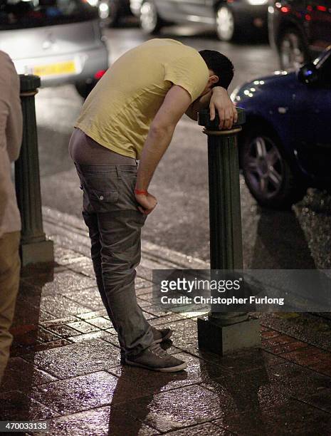 Young man uses a bollard for support as revellers walk and gather between the various pubs and clubs in Broad Street, the heartland of nightclubs and...