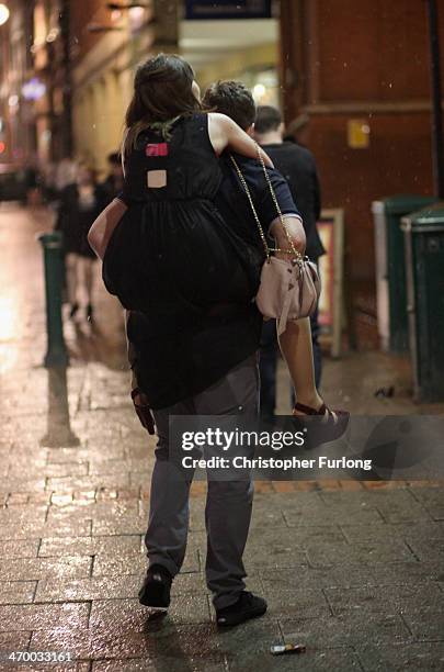 Young man carries his girfriend as revellers walk and gather between the various pubs and clubs in Broad Street, the heartland of nightclubs and bars...