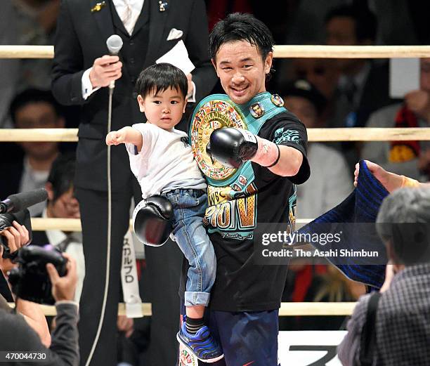 Champion Shinsuke Yamanaka of Japan celebrates his seventh round knock-out win against challenger Diego Santillan of Argentina with his child during...