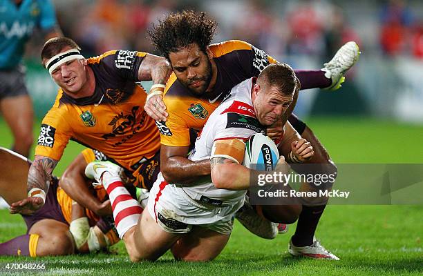 Trent Merrin of the Dragons is tackled by Sam Thaiday and Josh McGuire of the Broncos during the round seven NRL match between the St George...