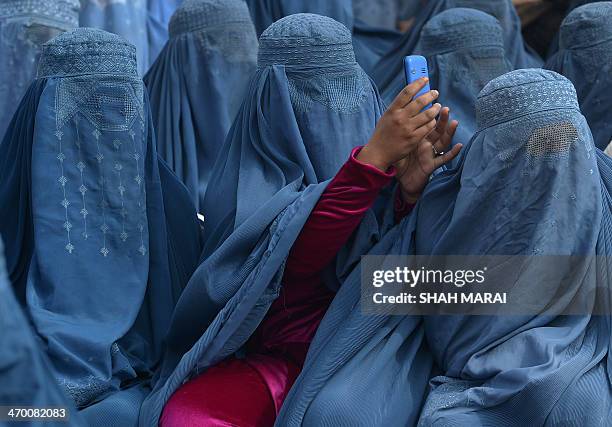 An Afghan woman takes a photograph with her mobile phone as she and supporters attend the election rally of Afghan presidential candidate Abdullah...