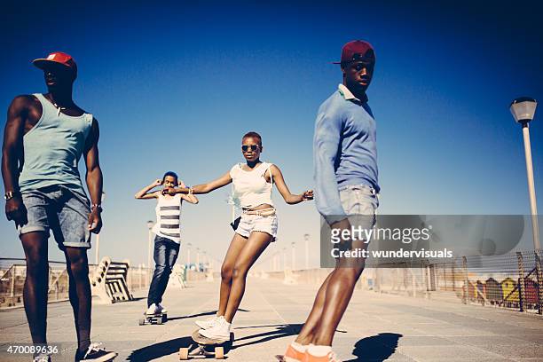 cool african american teenagers longboarding at the beach - coolpad stockfoto's en -beelden