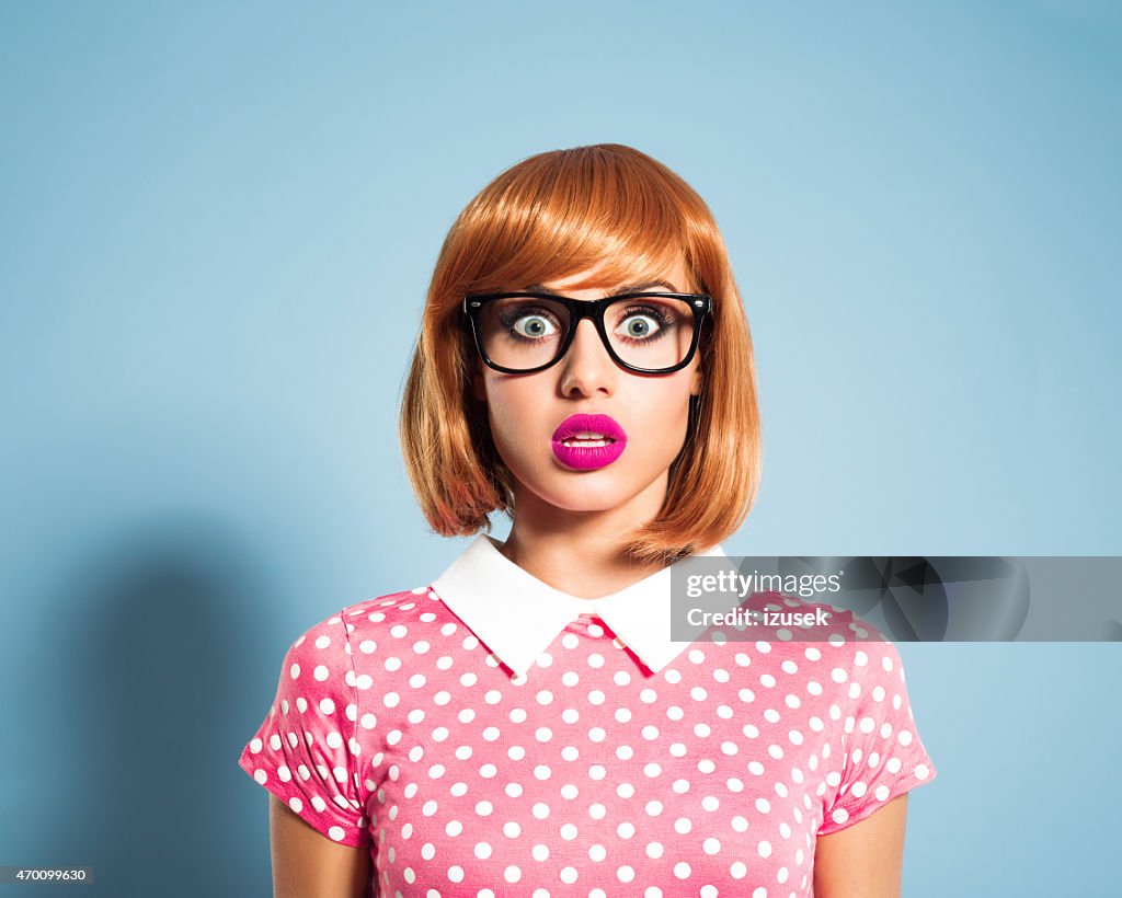 Surprised red hair young woman wearing polka dot dress