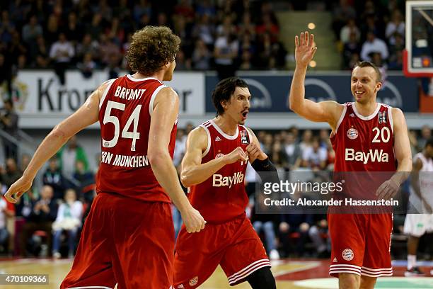 John Bryant of Muenchen celebrates scoring a point with his team mates Nihad Djedovic and Dusko Savanovic during the Beko Basketball Bundesliga match...