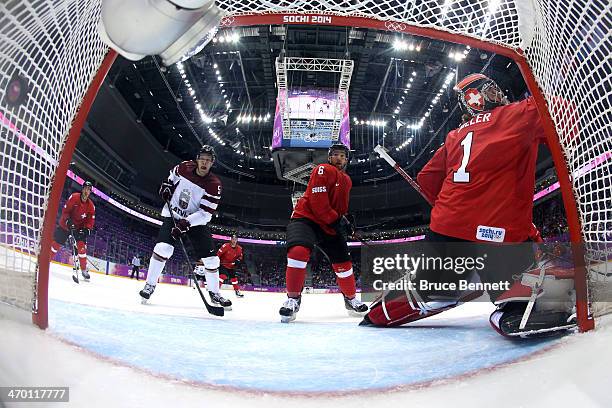 Jonas Hiller of Switzerland gives up a goal in the first period to Lauris Darzins of Latvia during the Men's Ice Hockey Qualification Playoff game on...