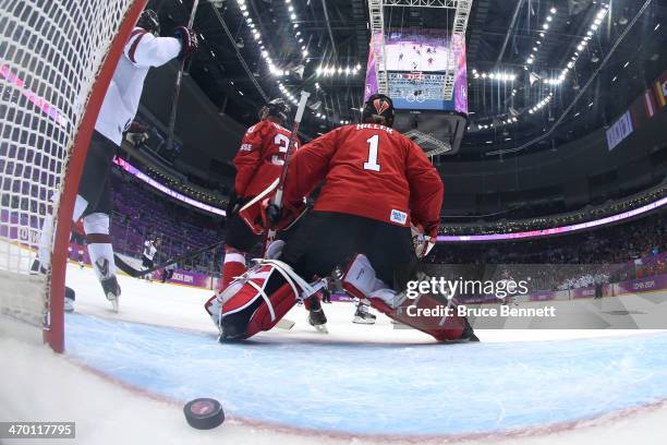 Jonas Hiller of Switzerland gives up a goal in the first period to Oskars Bartulis of Latvia during the Men's Ice Hockey Qualification Playoff game...