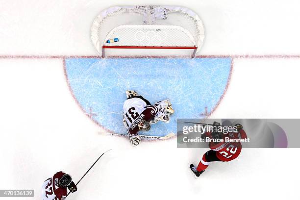 Edgars Masalskis of Latvia gives up a goal in the second period to Martin Pluss of Switzerland during the Men's Ice Hockey Qualification Playoff game...