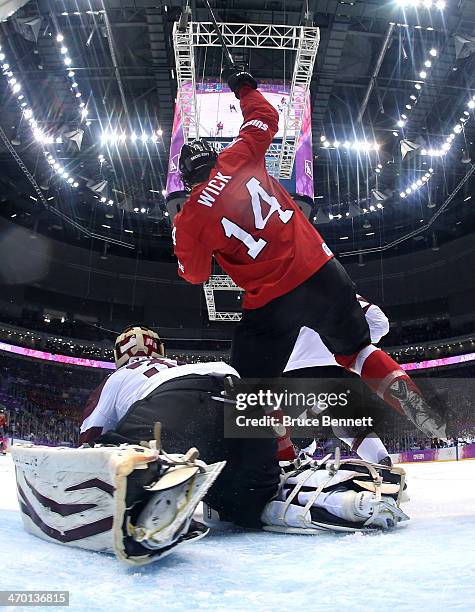 Roman Wick of Switzerland falls to the ice after tripping over Edgars Masalskis of Latvia during the Men's Ice Hockey Qualification Playoff game on...