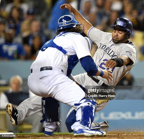 Wilin Rosario of the Colorado Rockies is tagged out at the plate by Yasmani Grandal of the Los Angeles Dodgers during the fourth inning at Dodger...