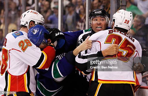Linesmen Jay Sharrers tries to separate Brandon Bollig of the Calgary Flames and Luca Sbisa of the Vancouver Canucks during Game Two of the Western...