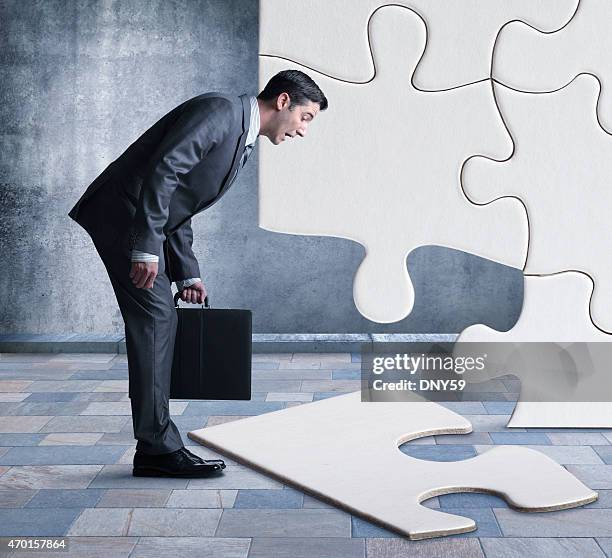 businessman bent over looking at missing piece of puzzle - leaning over stock pictures, royalty-free photos & images