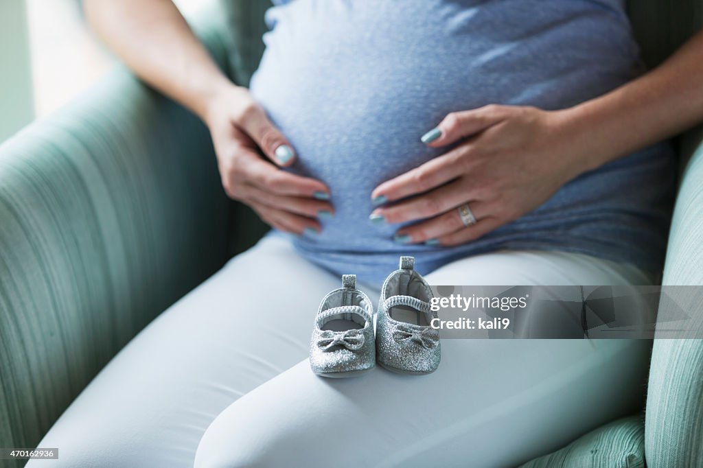 Grávida, botinhas de bebé no colo