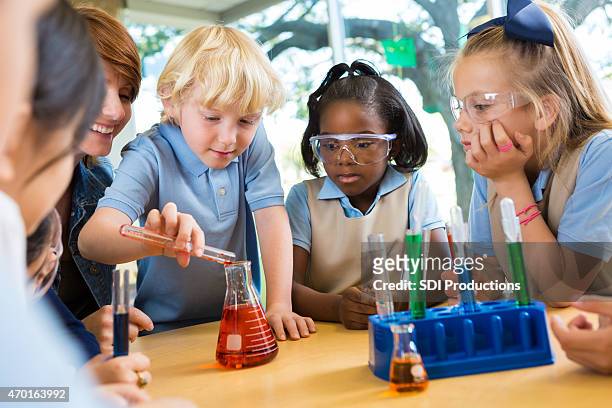 elementary school students doing chemistry science experiment in class - private school uniform stock pictures, royalty-free photos & images
