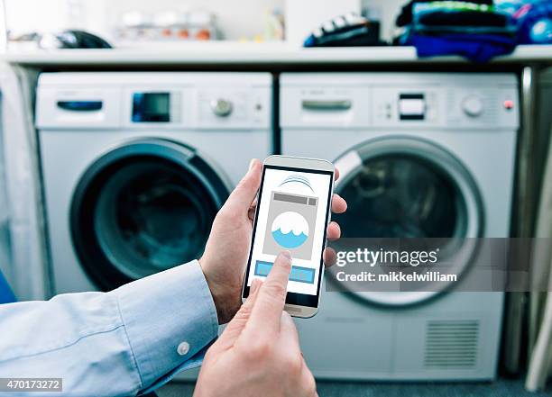 mobile phone with app used to control washing machines - iot stock pictures, royalty-free photos & images