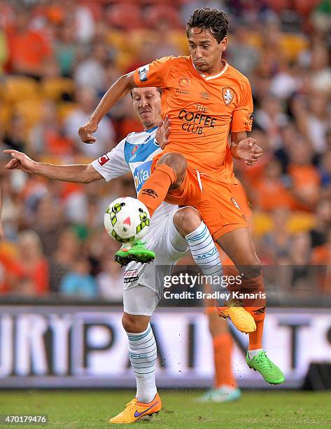 Adam Sarota of the Roar and Mark Milligan of the Victory challenge for the ball during the round 26 A-League match between the Brisbane Roar and...