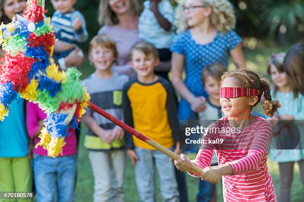 kleines mädchen mit augenbinde schlagen eine piñata - pineta stock-fotos und bilder