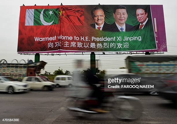 Pakistani commuters drive past a welcoming billboard featuring pictures of visiting Chinese President Xi Jinping and his Pakistani counterpart...