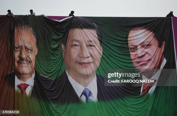 Pakistani labourers arrange a welcoming billboard featuring pictures of visiting Chinese President Xi Jinping and his Pakistani counterpart Mamnoon...